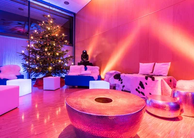 Winterliche Lounge im KU'KO Stimmungsbild im Saal Rosenheim mit Loungemöbeln im KU'KO mit Weihnachtsbaum. Farbige Strahler.